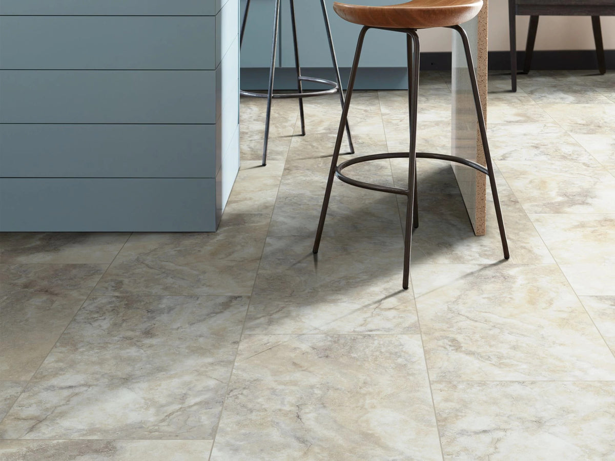 Blue island panels and a curved wooden barstool frame Pebble 1022V-01009 by Shaw Paragon Tile Plus, whose cream-and-gray stone pattern fills this modern kitchen detail.