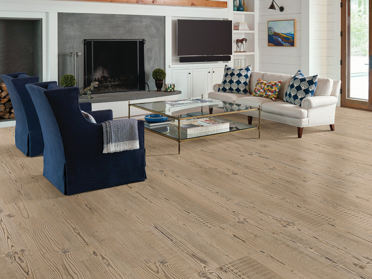 Repeated cross-grain markings give Shaw Anvil Plus 20 Mil Accent Pine (2357V-07063) visual texture below blue wingback chairs, a white sofa and a fireplace in this transitional living room.