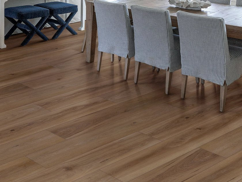 Shaw Fresh Take Windsor Brown wood-look vinyl planks display alternating brown shades and darker lengthwise grain beneath a wooden dining table and striped fabric chairs.