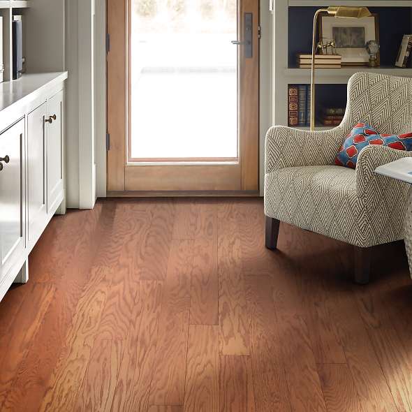 Living room view of Shaw Albright Oak 5.0 Gunstock engineered hardwood flooring, showing natural wood hardwood color near sofa seating and the open floor area.