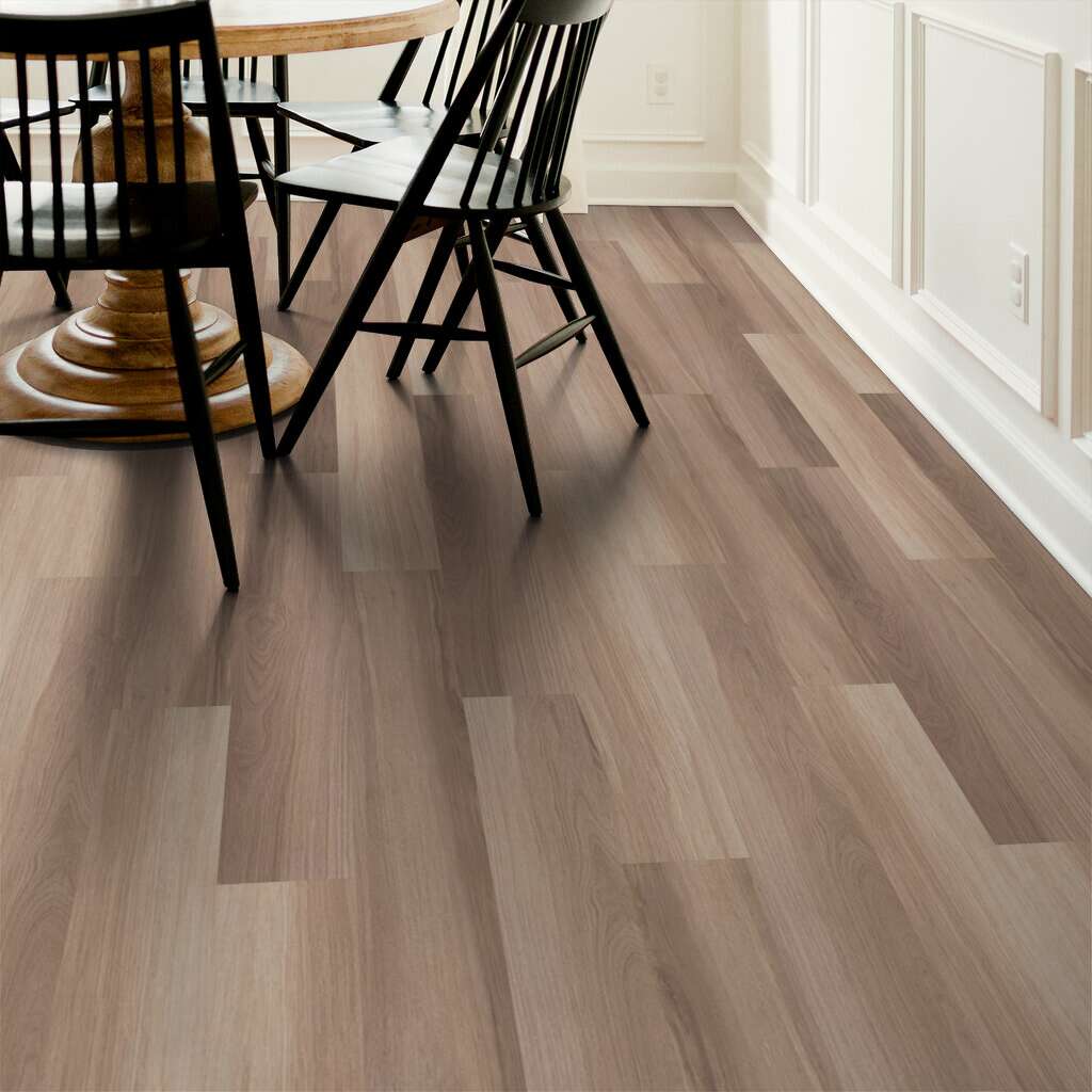 Brown wood-look planks beneath black dining chairs beside white wall paneling, supplied as Shaw Endura Plus Almond Oak 0736V-00154 vinyl flooring.