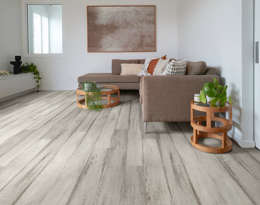 Dark grain streaks contrasts with pale gray vinyl planks around a living-room sectional with Shaw Endura Plus Fresh Driftwood 0736V-01160.