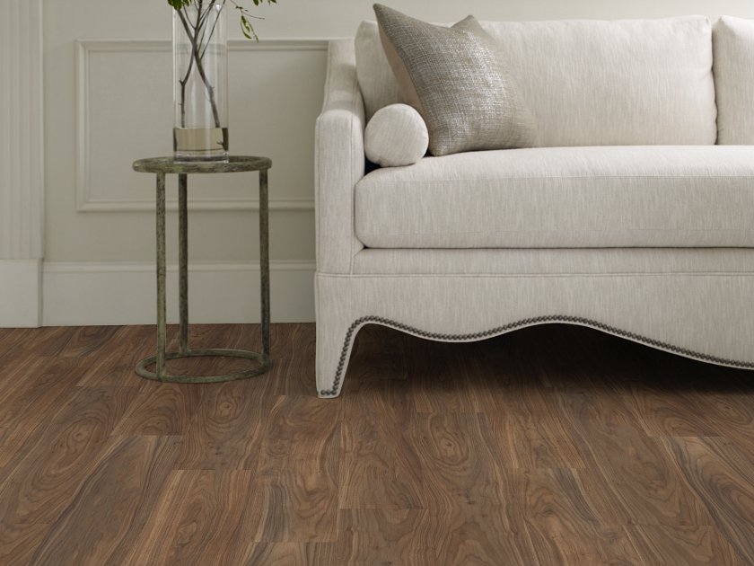 Deep brown coloring with swirling wood-look grain, frames a cream sofa in this close view of Shaw Endura Plus Modern Classic 0736V-07295 vinyl floor.