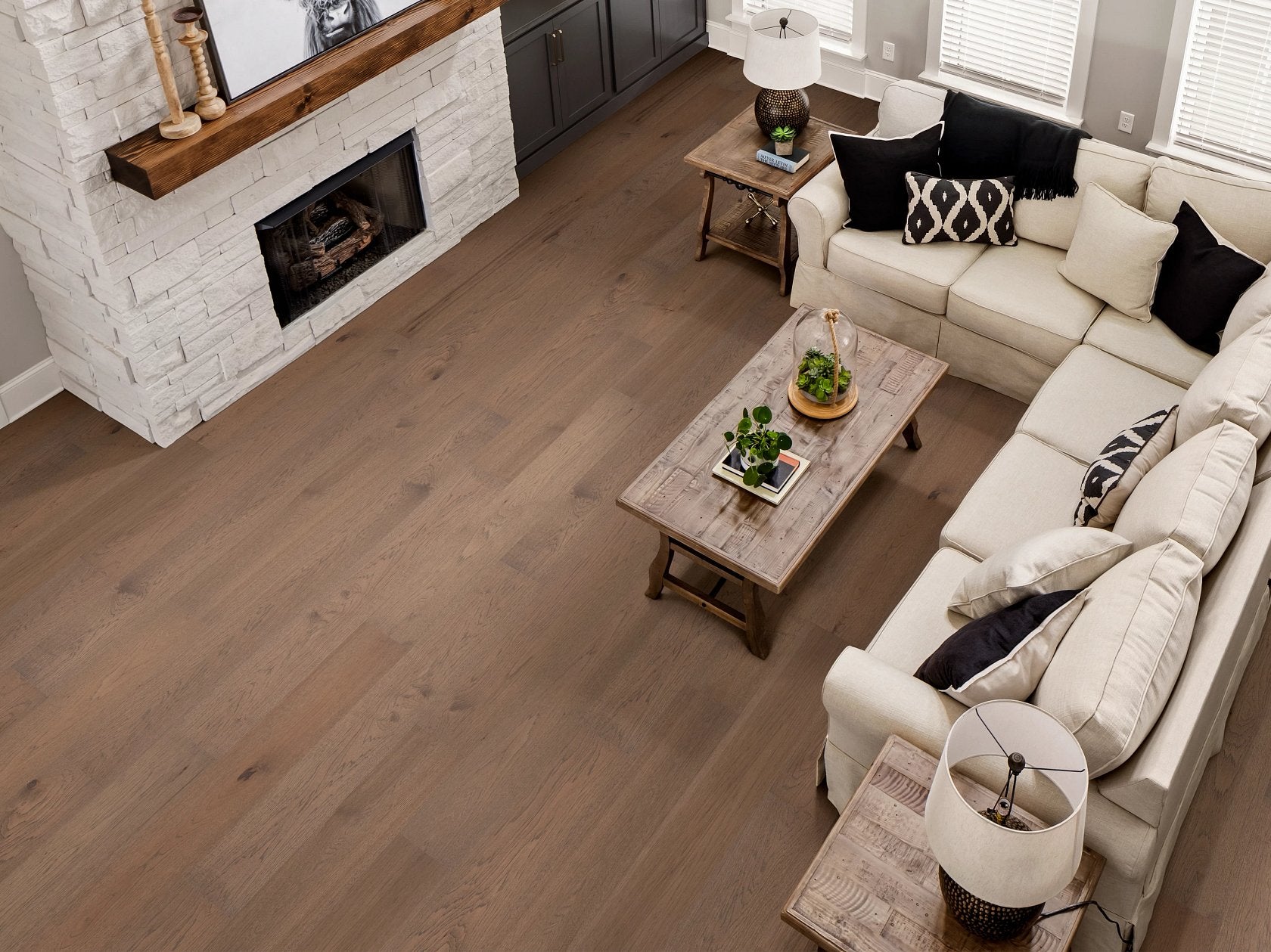 Shaw Landmark Sliced Hickory Denali engineered hardwood flooring gives this living room a polished look, with natural wood color around sofa seating and the open floor area.