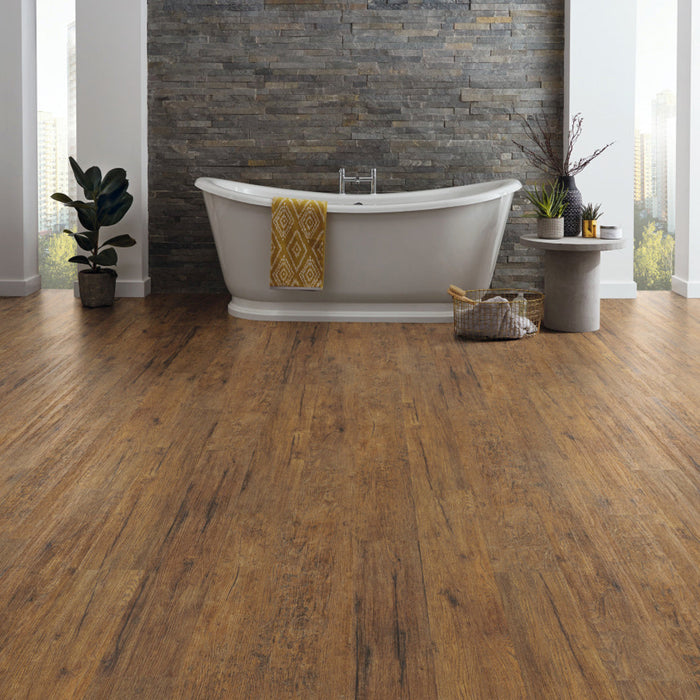 A modern bathroom featuring a freestanding tub, karndean korlok reserve vintage oregon oak flooring, a stone accent wall, and decorative plants and accessories.