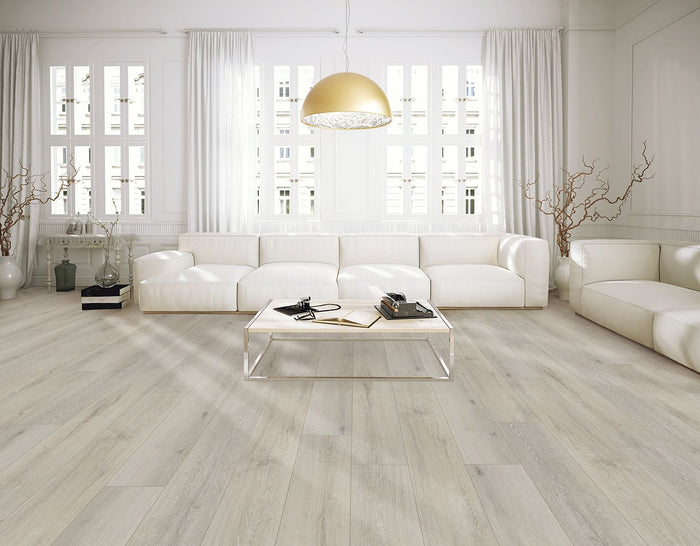 Bright living room with two white armchairs, gold accent table, and Shaw Floorté Classic Ambition Silk luxury vinyl plank flooring in a soft neutral tone.