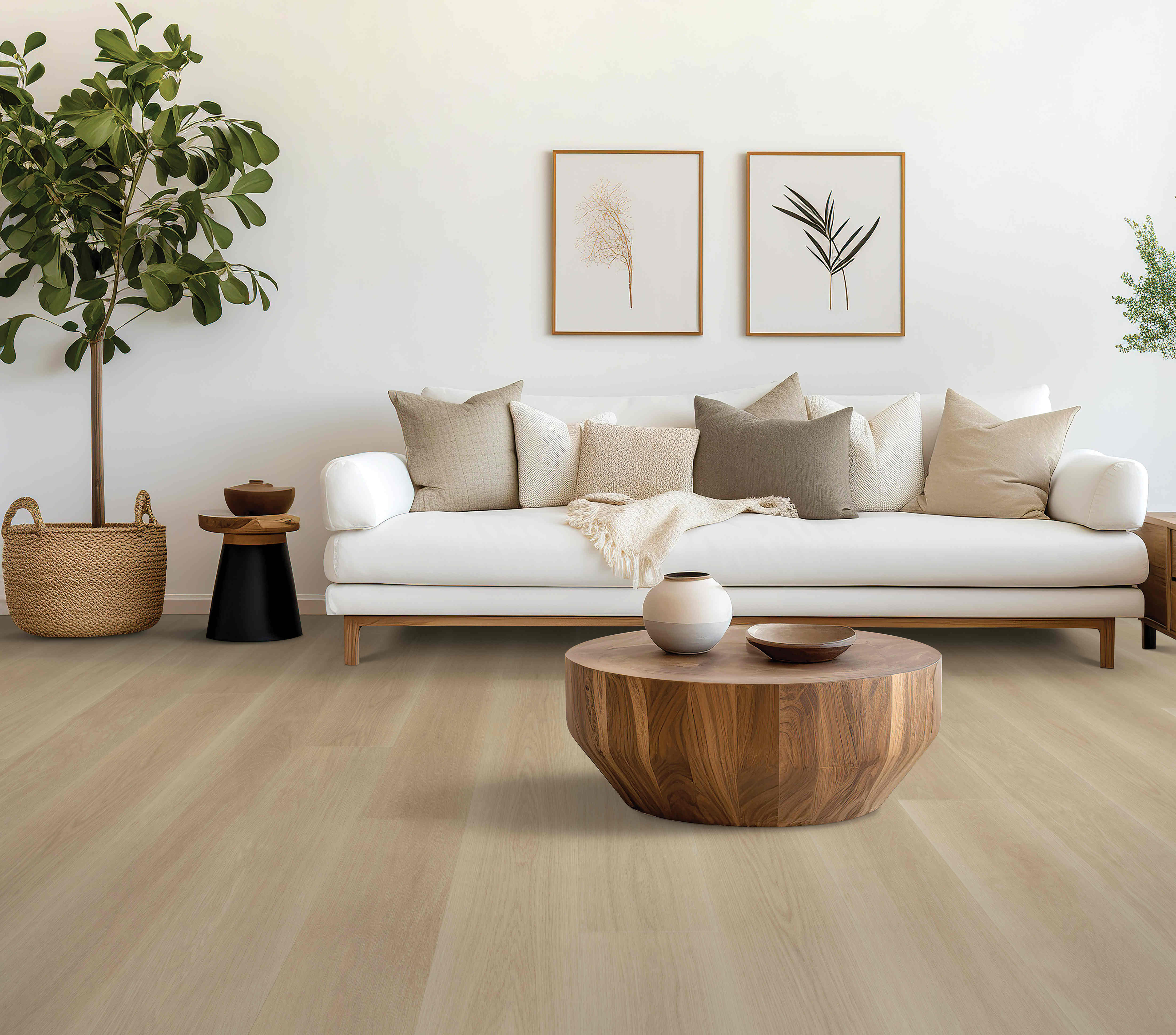 A cozy living room featuring a Mohawk Puretech Select Flooring, white couch with various pillows, a wooden coffee table, plants, and framed botanical art on the wall.