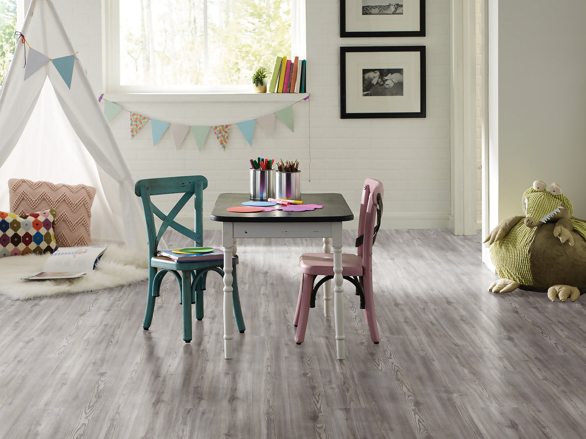 The linear pine look of Shaw Paladin Plus Fresh Pine (0278V-05052) runs below a small children's table, colorful chairs and a fabric tent in this eclectic playroom