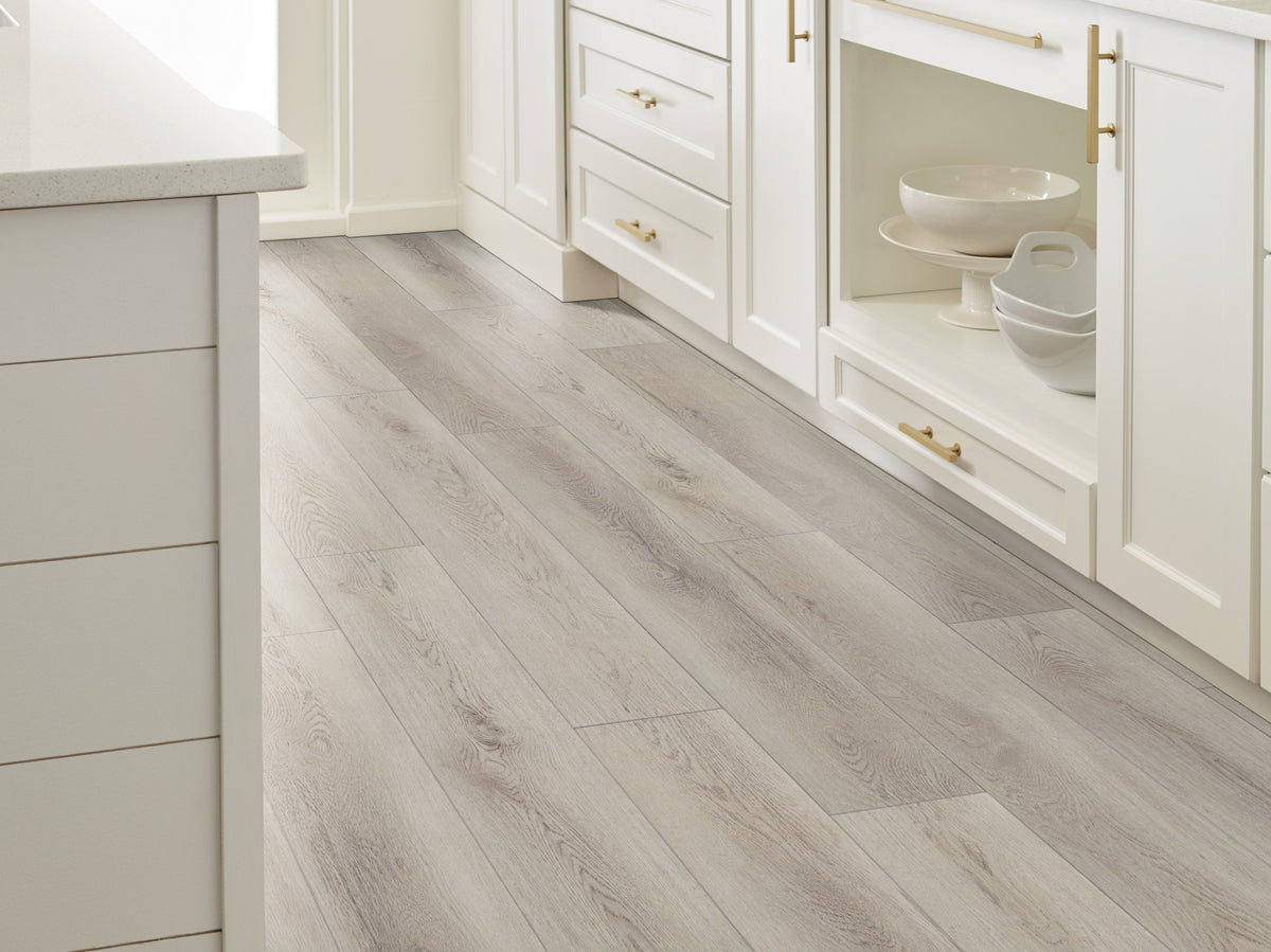 Pale gray-beige flooring brightens the space between white cabinets in this traditional kitchen, showing the understated coloring of Shaw Paladin Plus Warm Grey (0278V-05220).