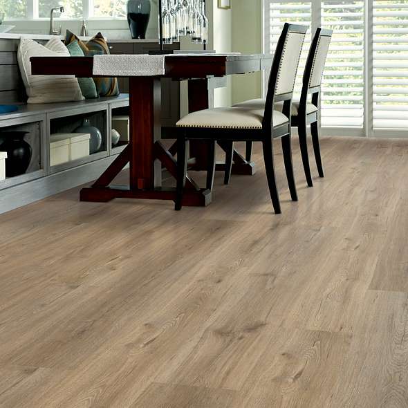 Beside a built-in dining bench, darker knots stand out against tan Shaw Endura Plus Wild Dunes 0736V-07089 vinyl planks with wood-look grain.