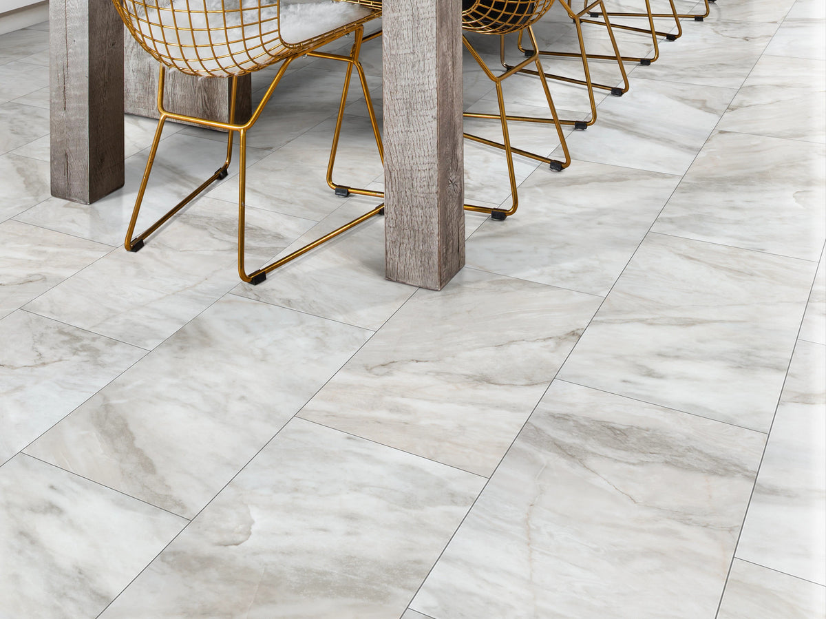Gold wire dining chairs and substantial timber table legs stand on Catalina 1022V-01109 from Shaw Paragon Tile Plus in a contemporary dining-room close-up.