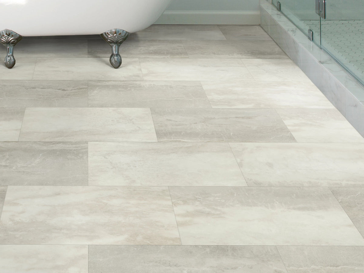 Silver claw feet and a glass shower enclosure border Mist 1022V-05261 by Shaw Paragon Tile Plus, laid in pale alternating tones across a traditional-style bathroom.