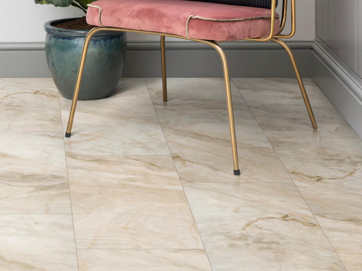A blush velvet chair with a gold frame sits beside a teal planter on Jordan 1022V-06019 by Shaw Paragon Tile Plus in a glamorous paneled corner.