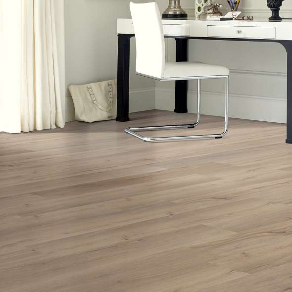 Taupe and brown boards of Shaw Endura Plus Driftwood 0736V-01056 spread beneath a white desk chair, showing vinyl flooring in a workspace.
