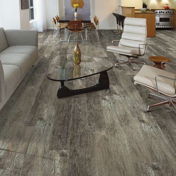 Pronounced dark streaks cut through gray Shaw Endura Plus Smoky Oak 0736V-00556 wood-look vinyl in an open living area with white chairs.
