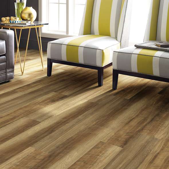 Golden boards interspersed with darker brown planks lead toward striped chairs, showing Shaw Endura Plus Tawny Oak 0736V-00203 vinyl in a sitting room.