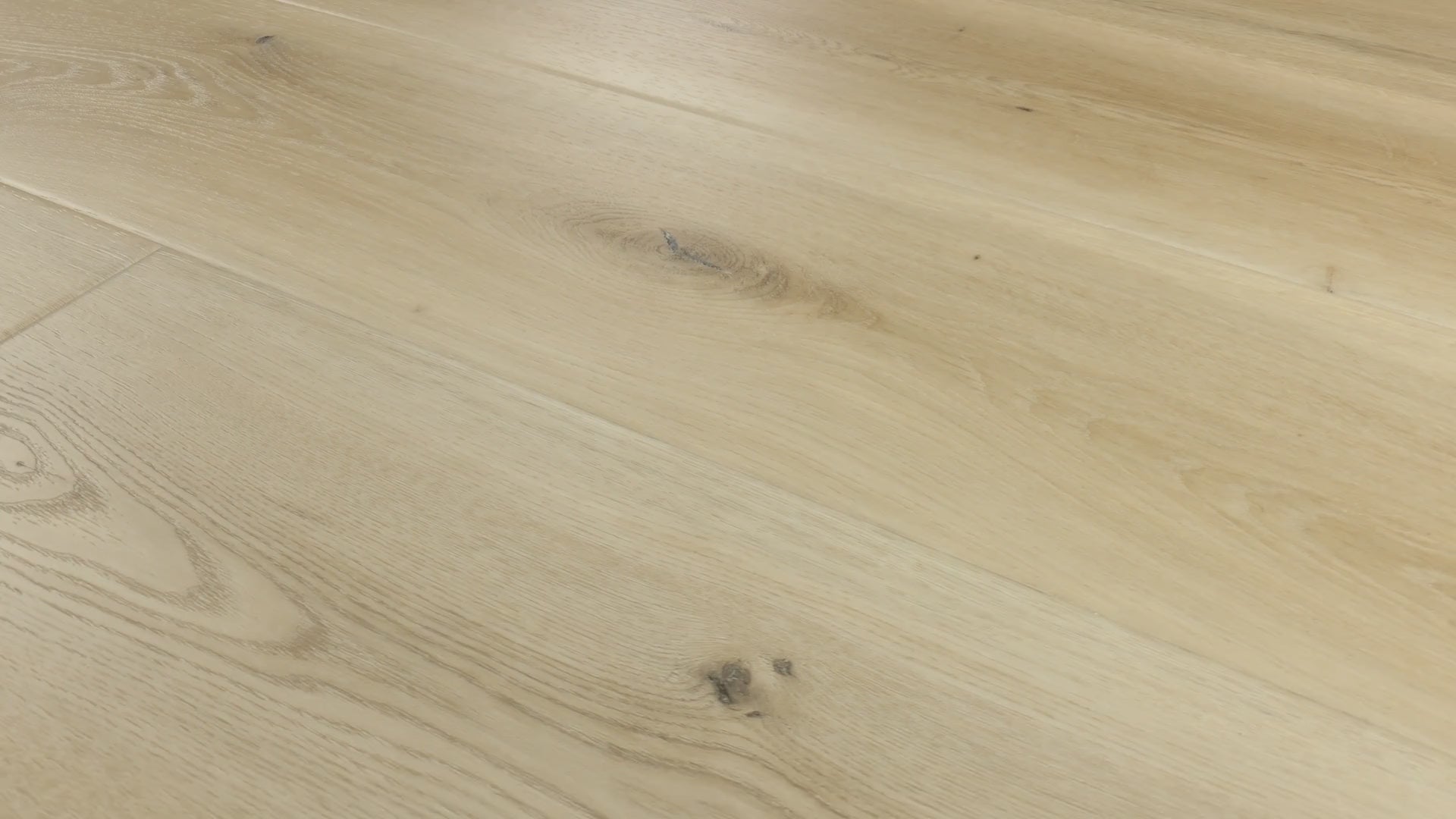Close-up camera slowly pans across installed COREtec Salt luxury vinyl plank flooring, highlighting its light oak tones, natural wood grain, knots and wide-plank layout.
