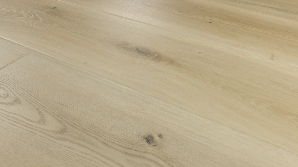 Close-up camera slowly pans across installed COREtec Salt luxury vinyl plank flooring, highlighting its light oak tones, natural wood grain, knots and wide-plank layout.
