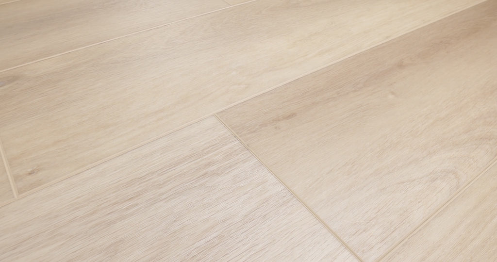Close-up camera pans across COREtec Aurora luxury vinyl plank flooring, highlighting its pale natural oak tones, subtle wood grain and wide-plank design.
