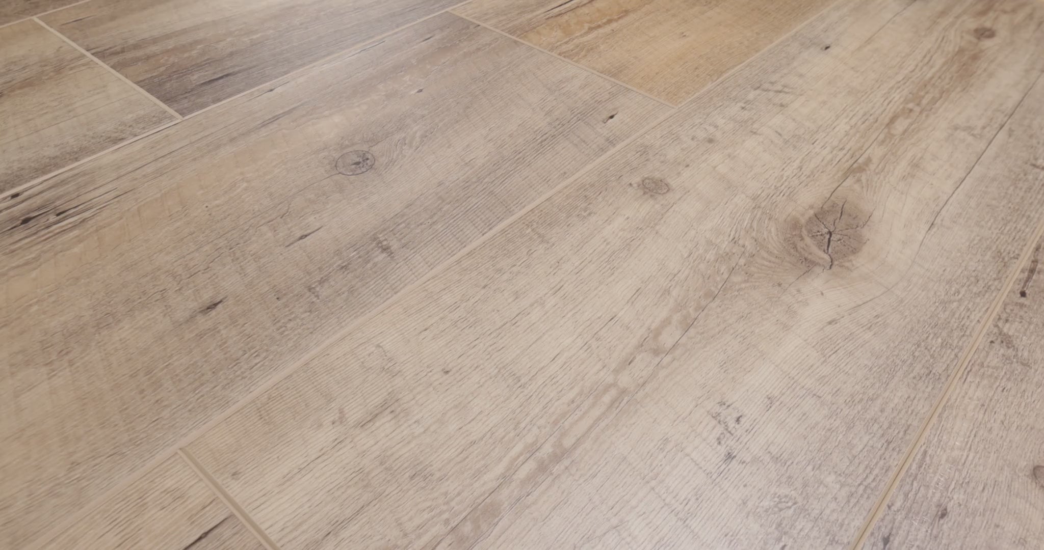 Close-up camera pans across COREtec Nares luxury vinyl plank flooring, highlighting its light natural oak color, realistic wood grain, knots and wide-plank design.
